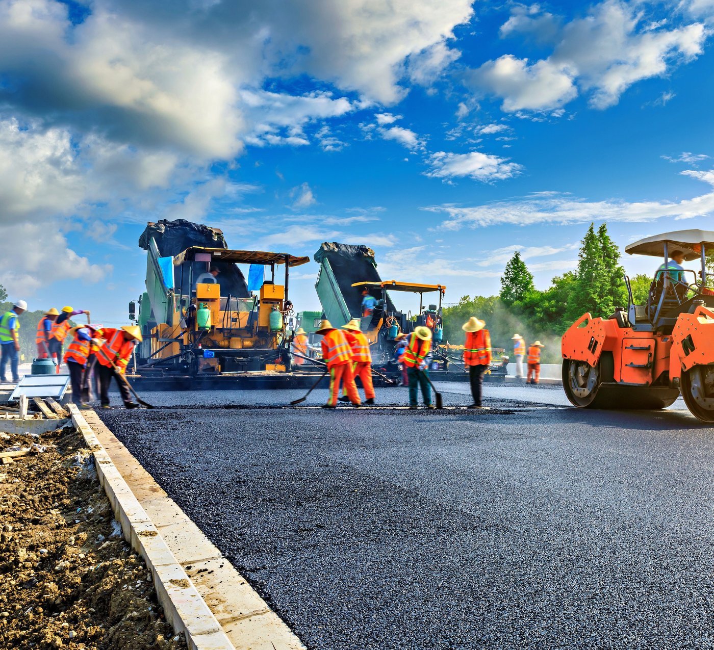 A road construction crew laying asphalt with heavy machinery